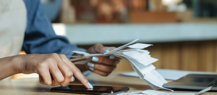 A woman's hand holding a paper that looks like computing