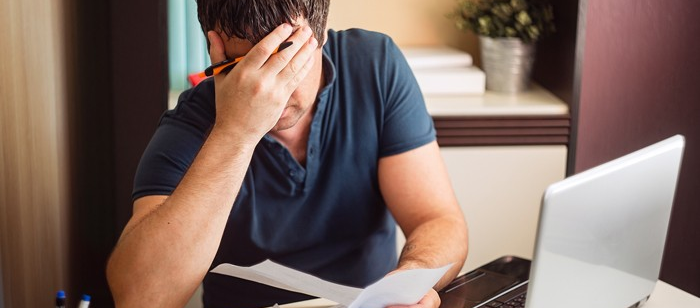 a man holding papers or documents and the other hand on his face looking problematic